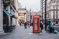 People walking past red phone booth in Haymarket, City of Westminster, London, UK