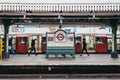 People walking past the station name sign on the outdoor platform of Golders Green tube station, London, UK Royalty Free Stock Photo