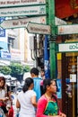 People walking past a street direction sign