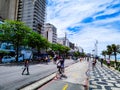 People walking on the promenade with trees, buildings