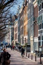 People walking and riding bicycles at the beautiful cobblestone streets next to the canals of Amsterdam