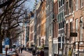 People walking and riding bicycles at the beautiful cobblestone streets next to the canals of Amsterdam