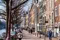 People walking and riding bicycles at the beautiful cobblestone streets next to the canals of Amsterdam