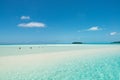 People enjoy walking through shallow turquoise water in paradise with white sand, blue sky, Cook Islands, South Pacific Ocean Royalty Free Stock Photo