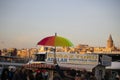 People walking in the square and the ferry port. A colorful umbrella is high to guide tourists