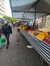 People walking by the stands of an open market for fruit and vegetables, popularly known as feira livre in Portuguese.