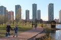 people walking on street alley, benches in spring fall season with green vibrant saturated foliage trees, sitting on benches