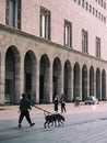 people walking their dogs in the middle of the sidewalk in front of some buildings