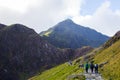 People walking to the summit of a mountain through a pathway surrounded by beautiful landscapes in Snowdonia, Wales Royalty Free Stock Photo