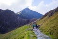 People walking to the summit of a mountain through a pathway surrounded by beautiful landscapes in Snowdonia, Wales