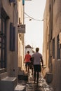 People walking towards windmills during sunset on a street in Hora Mykonos Town, Mykonos, Greece Royalty Free Stock Photo