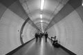 People walking in tunnel and man playing harp in London