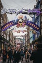 People walking under Bohemian Rhapsody themed Christmas lights in Carnaby Street, London, UK