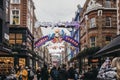 People walking under Bohemian Rhapsody themed Christmas lights in Carnaby Street, London, UK