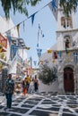 People walking under colourful bunting on a narrow street in Hora Mykonos Town, Greece Royalty Free Stock Photo