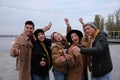 People in warm clothes holding burning sparklers on pier