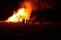 People watching a bonfire burn at night