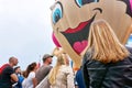 People watching a large large balloon with smiling face