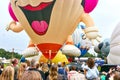 People watching a large large balloon with smiling face