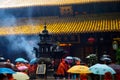 People wear raincoats to pray for blessings and incense during heavy rain at the Harmony Temple on Mount Putuo in Hangzhou, China