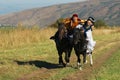 People wearing national dresses ride on horseback at countryside, Almaty, Kazakhstan. Royalty Free Stock Photo