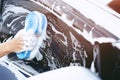 People worker man holding hand blue sponge and bubble foam cleanser window for washing car. Concept car wash clean. Royalty Free Stock Photo