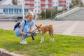 People working as dog-sitter, girl with french poodle dog in park. The young hispanic woman picks up her pet's poo with