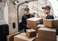 People working for a delivery company. Couriers load packages into a car