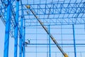 People working on an industrial blue infrastructure near a crane