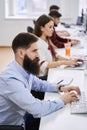 People working in modern IT office. Group of young and experienced programmers and software developers sitting at desks