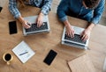 Two people working on laptops on a wooden desk, top view Royalty Free Stock Photo