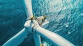 People works on top of wind turbine in sea, engineers perform maintenance of windmill in ocean, aerial view. Concept of energy, Royalty Free Stock Photo