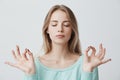 People, yoga and healthy lifestyle. Gorgeous young blonde woman dressed in light blue sweater keeping eyes closed while Royalty Free Stock Photo