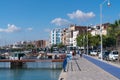 Peoplem walking on seafront promenade with boats moored port of L`Ampolla, Catalonia, Tarragona Province Spain