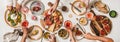 Peoples hands with rose wine and foods over various snacks table Royalty Free Stock Photo