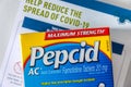 Pepcid AC antacid medicine in front of a Covid-19 prevention document