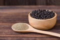 Black pepper seeds or peppercorns  dried seeds of piper nigrum  in wooden bowl Royalty Free Stock Photo