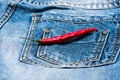 Pepper on back pocket of blue jeans. Pocket of jeans with red chilly pepper, denim background. Hot sensations concept