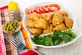 Pepper, bowl with green peas, fork on napkin, partitioned dish with patties, parsley, slices of tomato on wooden table Royalty Free Stock Photo