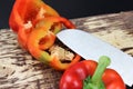 A pepper cut into two halves with a sharp knife. Knife lay next to cuttable pepper