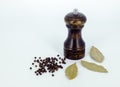 A pepper mill with black pepper corns in white background. Royalty Free Stock Photo