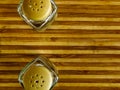 Pepper pot and salt shaker stand empty on a cutting board on a white background