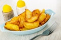 Pepper and salt, blue plate with slices of fried potato, fork on table Royalty Free Stock Photo