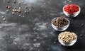 Pepper set. Black, white and pink rose peppers in bowls, assorted spices on gray kitchen table, selective focus
