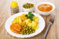 Pepper shaker, bowls with green peas, squash caviar, plate with fried potato, green peas, squash caviar, fork on table Royalty Free Stock Photo