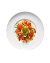 The pepper tomato salad elegantly arranged on a white plate with a basil garnish, white background