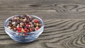 Peppercorns mix. Black, white, green and red pepper corns in a glass bowl on wood background. Piper nigrum Royalty Free Stock Photo