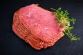 Peppered roast beef pastrami slices on black stone background with herbs Royalty Free Stock Photo