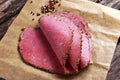 Peppered roast beef slices on paper with grains of coloured pepper.