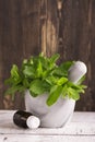 Peppermint oil and fresh mint leaves over wooden table